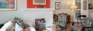 Living room with white brick fireplace, with a bright color on top.