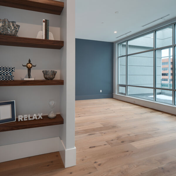 Photo of primary bedroom, it is a vacant room with floor to ceiling windows and shelving